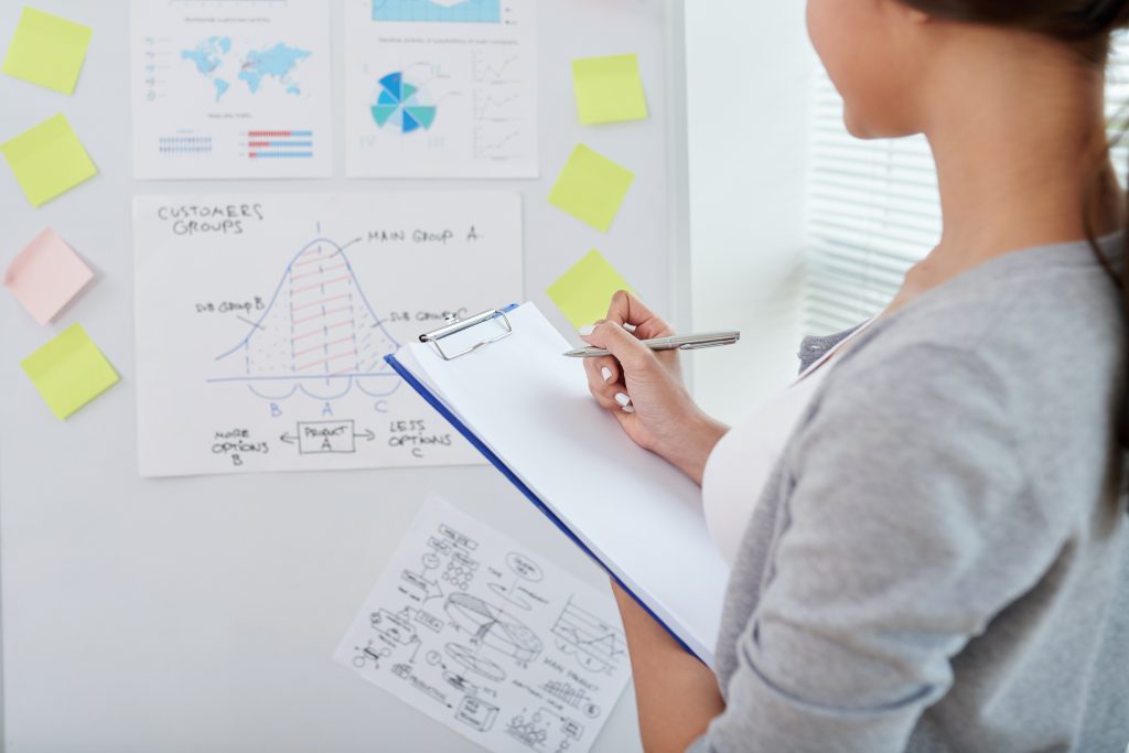 Cropped image of business lady taking notes when analyzing statistics